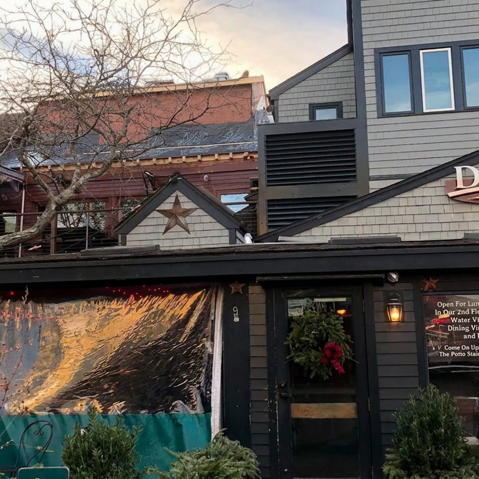 Exterior of Diecxs restaurant with dark wood siding, star decorations, outdoor seating, and festive greenery by the entrance.